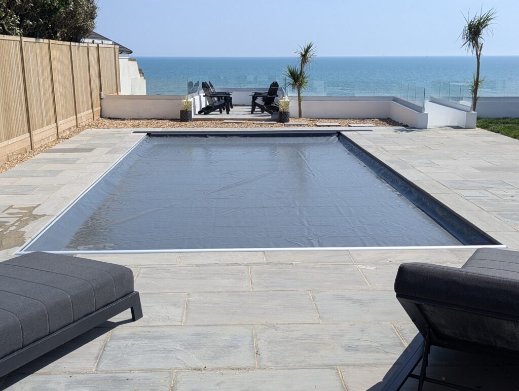 Grey swimming pool cover on a swimming pool overlooking the beach