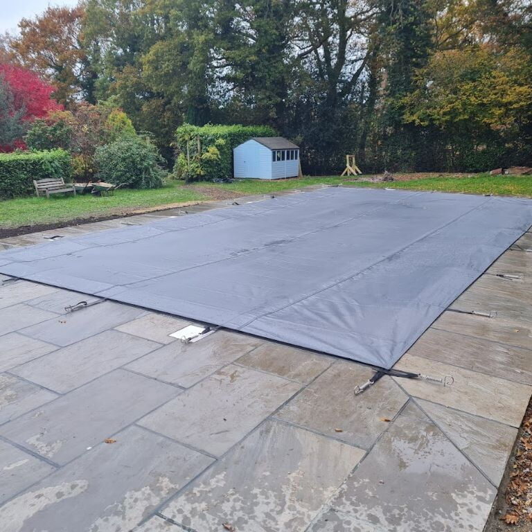 A rectangle outdoor swimming pool with dark pool cover and surrounding patio